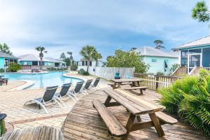 a patio with wooden tables and chairs next to a pool at 4014 Rookery 3 Cottage with two Pools and Beach Amenities in Gulf Highlands