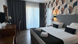a hotel room with a large bed and a desk at Hotel Le Bourgogne in Évian-les-Bains