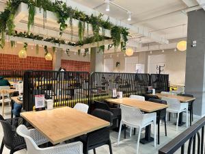 Un restaurante con mesas de madera y sillas blancas. en Rio Inn hotel в районе EXPO, en Astana