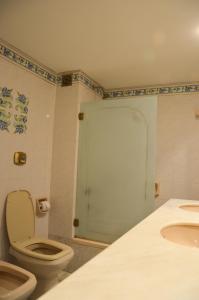 a bathroom with a toilet and a green door at Hotel Algeciras in Pinamar