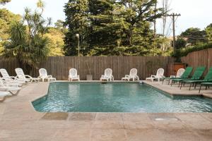 a swimming pool with lawn chairs and a bunch ofitures at Hotel Algeciras in Pinamar