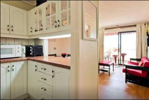 a kitchen with white cabinets and a living room at Departamento Reñaca in Viña del Mar