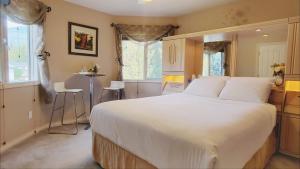 a bedroom with a large white bed and a table at Cornerstone Bed and Breakfast in Revelstoke