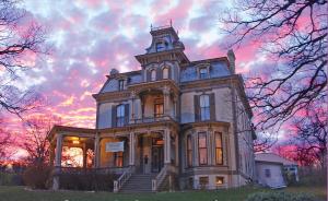 una casa vieja con una puesta de sol en el fondo en Garth Woodside Mansion Bed and Breakfast en Hannibal
