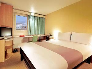 una camera d'albergo con un grande letto e una TV di ibis Carlisle City Centre a Carlisle
