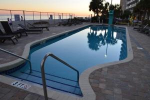a large swimming pool with a sunset in the background at Modern Decor Stunning Ocean View Condo Sleeps 8 in Myrtle Beach