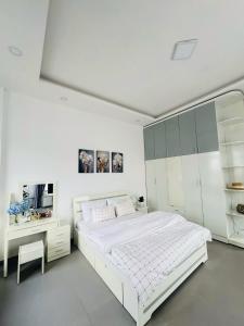 a white bedroom with a large bed and a desk at Say Homestay - Venuestay in Da Thien