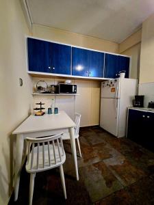 een keuken met een witte tafel en stoelen en een witte koelkast bij Feel's Like Home Apartment in Chios