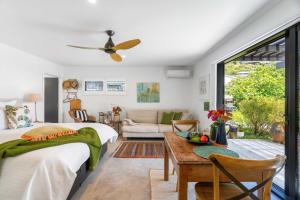 a bedroom with a bed and a table and a couch at Seagrass Studio Guesthouse - By the Beach in Tairua