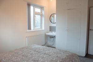 a bedroom with a bed and a sink and a window at Spacious 4-Bed Flat - 10 Mins to City Centre in Roundhay