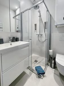 Un baño blanco con ducha y lavabo. en Le Grand Carré Versailles, en Versalles