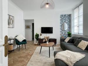 a living room with a couch and a tv at Le Grand Carré Versailles in Versailles