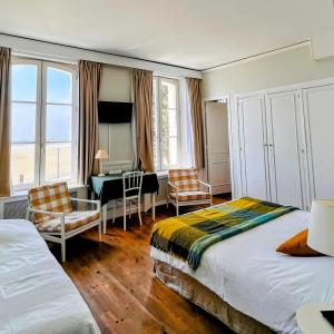 a hotel room with two beds and a desk and chairs at Hotel Restaurant Les Tourelles in Le Crotoy