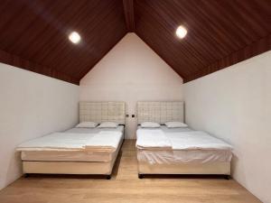 two beds in a room with white walls and wooden ceilings at Villa kumudini's 2 in Diyeng