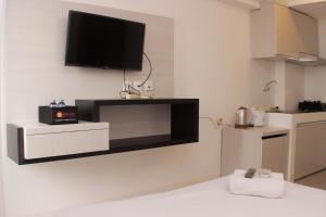 a living room with a flat screen tv on a wall at Cozy Living Studio at Urbantown Apartment Karawang By Travelio in Karawang