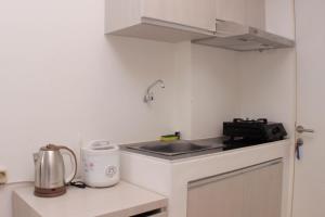 a small kitchen with a sink and a stove at Cozy Living Studio at Urbantown Apartment Karawang By Travelio in Karawang +3 photos