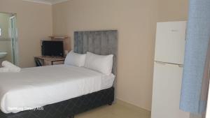 a bedroom with a bed with white sheets and a television at BAYSIDE Hotel & Self-catering ISIPINGO in Isipingo