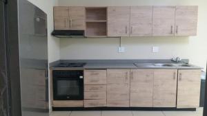 a kitchen with wooden cabinets and a stainless steel refrigerator at BAYSIDE Hotel & Self-catering ISIPINGO in Isipingo