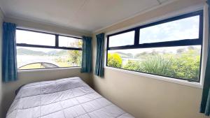 a bedroom with two windows and a bed in it at Pataua North By the Beach in Pataua