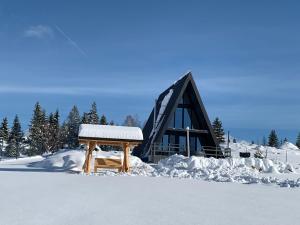 a wooden bench covered in snow in front of a building at Chalet Charme Bucovina in Coşna