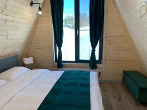 a bedroom with a bed and a large window at Chalet Charme Bucovina in Coşna +14 photos
