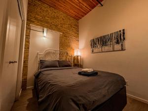 a bedroom with a large bed with a brick wall at Heart of the City: Cozy 2-Bed Loft in Winnipeg