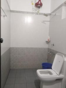a bathroom with a white toilet and a blue trash can at 2BHK Flat At Chalakudy Town Konuparamban Residence A1 in Kizhake Chālakudi