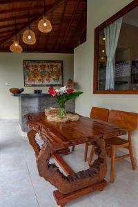 een houten tafel met een vaas met bloemen erop bij Villa Kanwa in Tampaksiring