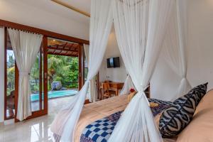 een slaapkamer met een bed met witte gordijnen bij Villa Kanwa in Tampaksiring