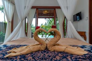 twee handdoeken in de vorm van een hart op een bed bij Villa Kanwa in Tampaksiring +27 foto's