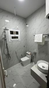 a white bathroom with a toilet and a sink at Wadi Front Apartment 2 in Nizwa