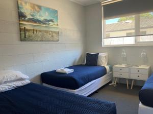 a bedroom with two beds and a window at Kalindo Merimbula in Merimbula