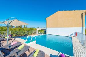 ein Swimmingpool mit Stühlen und einem Sonnenschirm in der Unterkunft Can Rafelino in Llubí