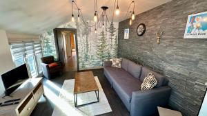 Una sala de estar con un sofá y una pared de ladrillos. en Les Oréades Le Mont Dore 10pers, en Le Mont-Dore