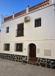 a white building with a gate and a door at Casa del Patio in Pinos del Valle +33 photos