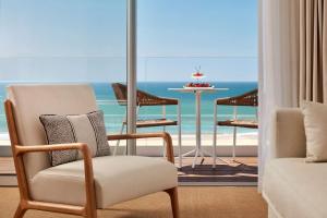 a room with a chair and a table and the ocean at Tivoli Marina Vilamoura in Vilamoura