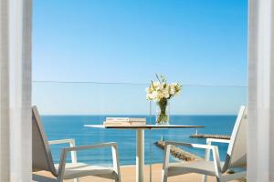 a table with chairs and a vase of flowers on it at Tivoli Marina Vilamoura in Vilamoura