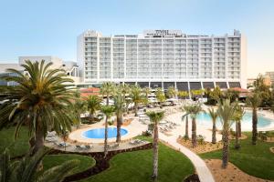 a hotel with palm trees and a large building at Tivoli Marina Vilamoura in Vilamoura