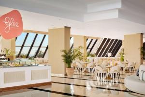 a restaurant with white chairs and tables and windows at Tivoli Marina Vilamoura in Vilamoura