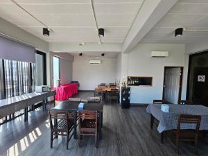 a living room with tables and chairs and a room with a couch at Polkadot Hostel in Phitsanulok