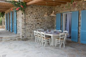 a table and chairs on a patio with blue shutters at Hacienda house in Antiparos