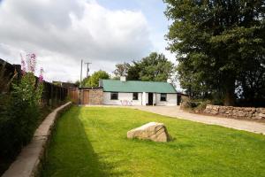 a house with a green roof and a rock in the yard at Croan Cottage in Mayobridge