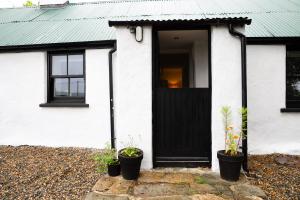 a white house with a black door and potted plants at Croan Cottage in Mayobridge +26 photos
