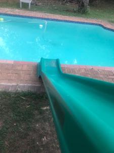 a swimming pool with a green slide in a yard at Uitpak in Barberton +17 photos
