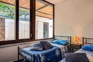 two beds in a room with two windows at Villa Demetra Capri - Pool and Relaxation in Anacapri