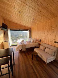 a bedroom with a bed and a couch and a window at Cabañas O Recuncho do Sor in O Barqueiro