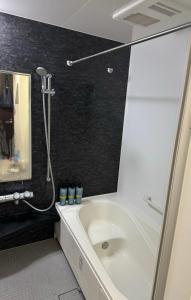 a bathroom with a white tub and a black wall at Kenzo House in Kawasaki +47 photos