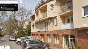 un edificio con coches aparcados al lado de una calle en Balcony Apartman Szeged, en Szeged