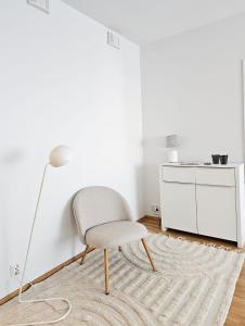 ein weißes Wohnzimmer mit einem Stuhl und einer Lampe in der Unterkunft City apartment Kuopio Satamankulma, free parking, wifi & sauna in Kuopio