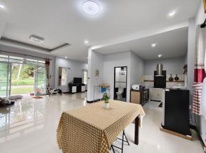 a living room with a table and a kitchen at BaanRatsitornHomestay in Langu